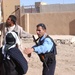 An Iraqi police officer directs a woman to a truck