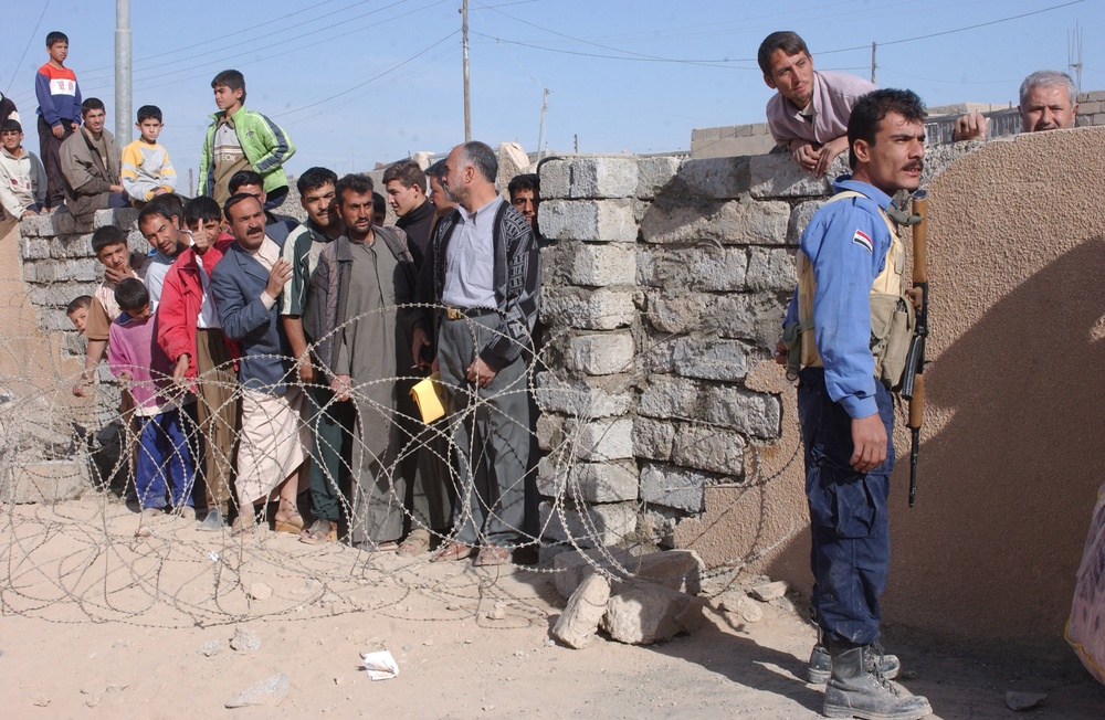 An Iraqi police officer stands guard at a gate