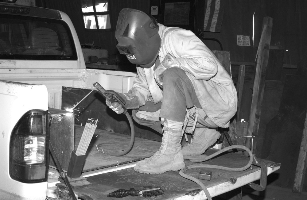 Sgt. Alan D. Mendenhall welds armor on an Iraqi police vehicle