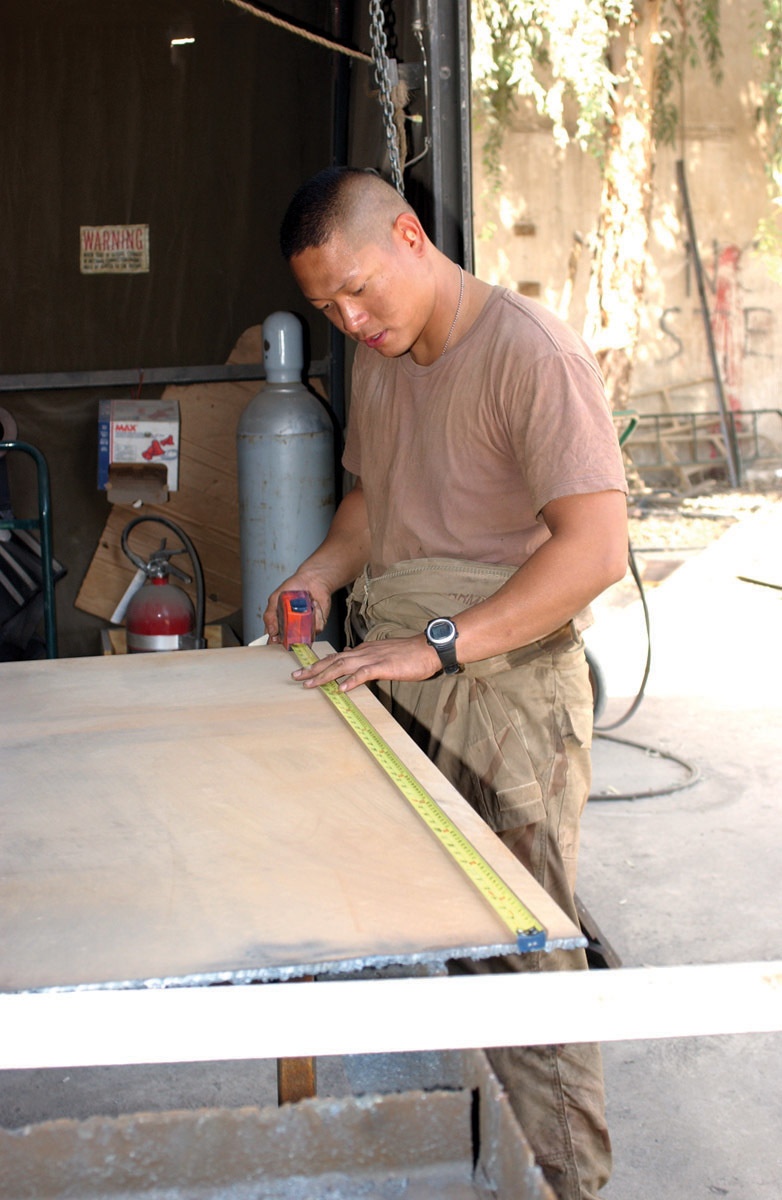 Pvt. Dan L. Trinidad measures and marks a sheet of heavy metal