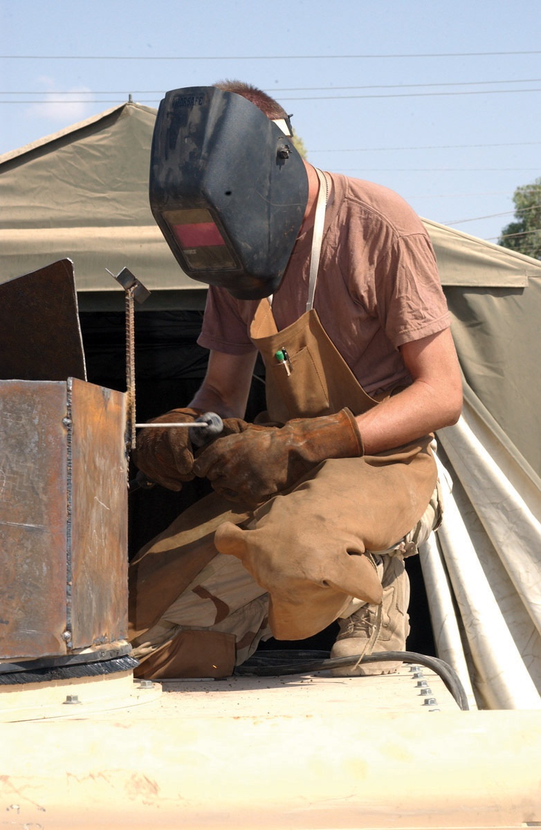 Spc. Eric W. Smith welds armor surrounding the gunner's turret of an