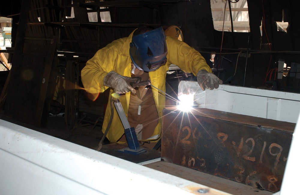 Sgt Alan D. Mendenhall welds armor to the bed of an Iraqi police vehicle