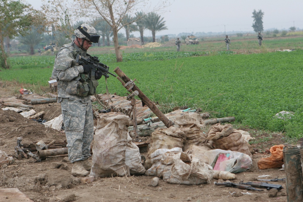 Sgt. 1st Class Cozad examines a weapons cache