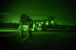 Two Soldiers walk in front of a Chinook
