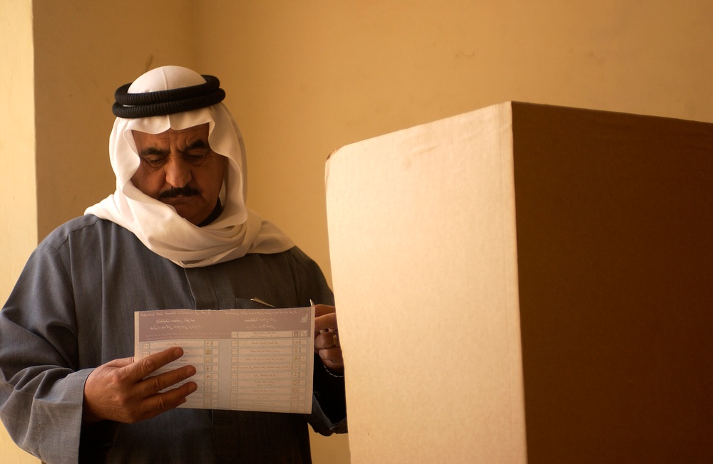 An Iraqi man marks yes or no on his ballot