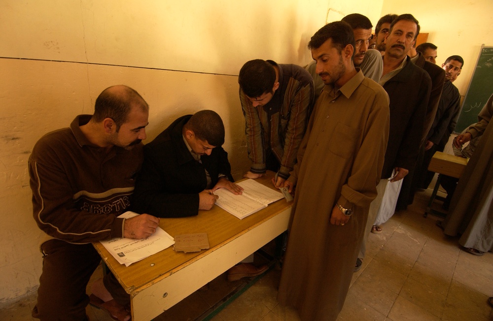 Voting officials check an Iraqi mans identification card