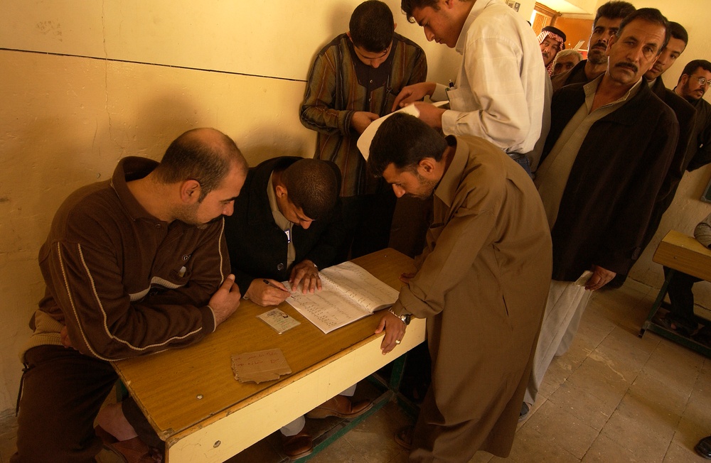 Voting officials check an Iraqi mans identification card