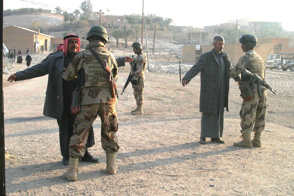 Iraqi voters are searched by Soldiers