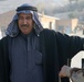 An Iraqi man holds his hands out as he is searched