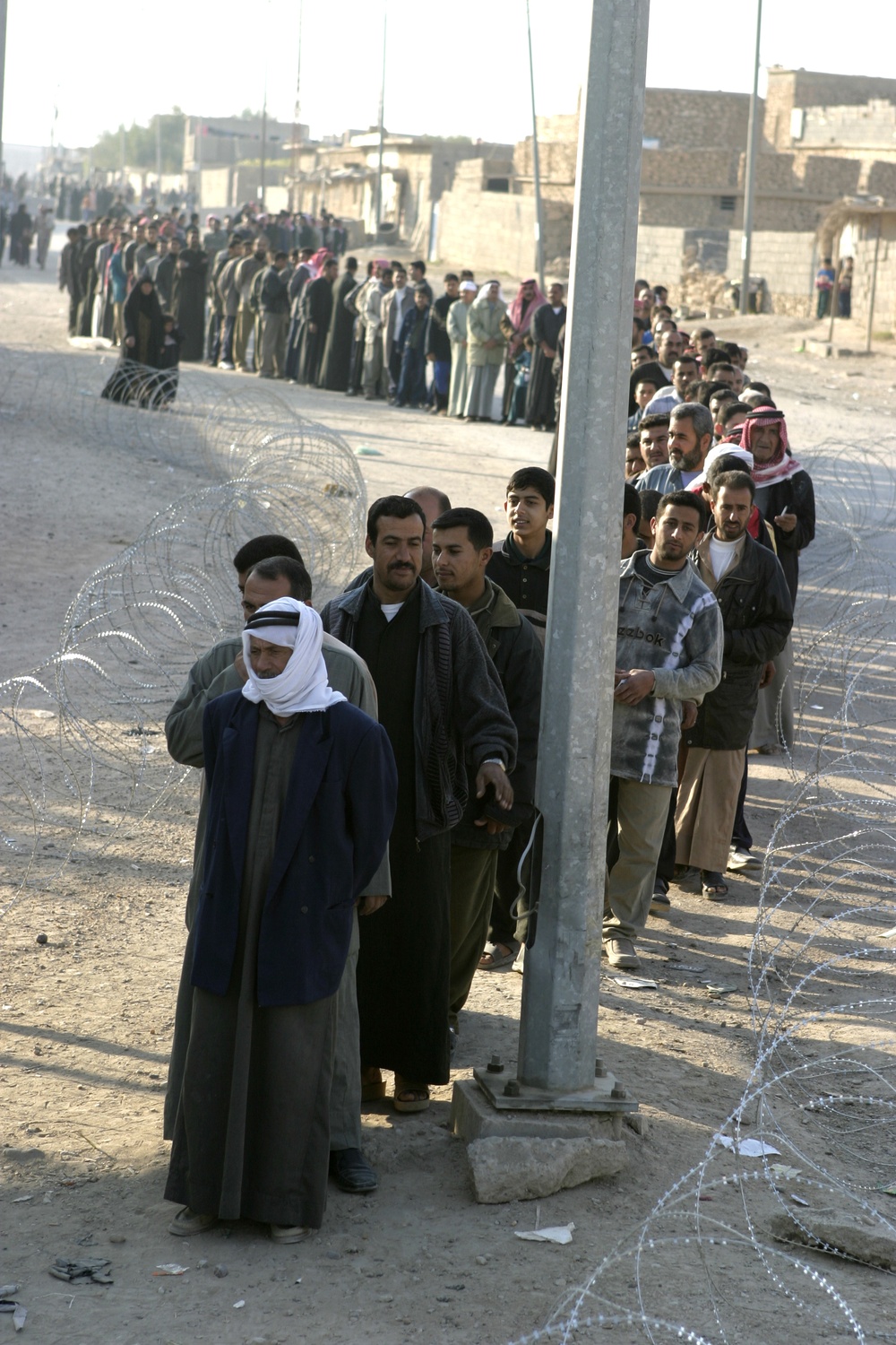 Iraqi men wait to enter the polling sites