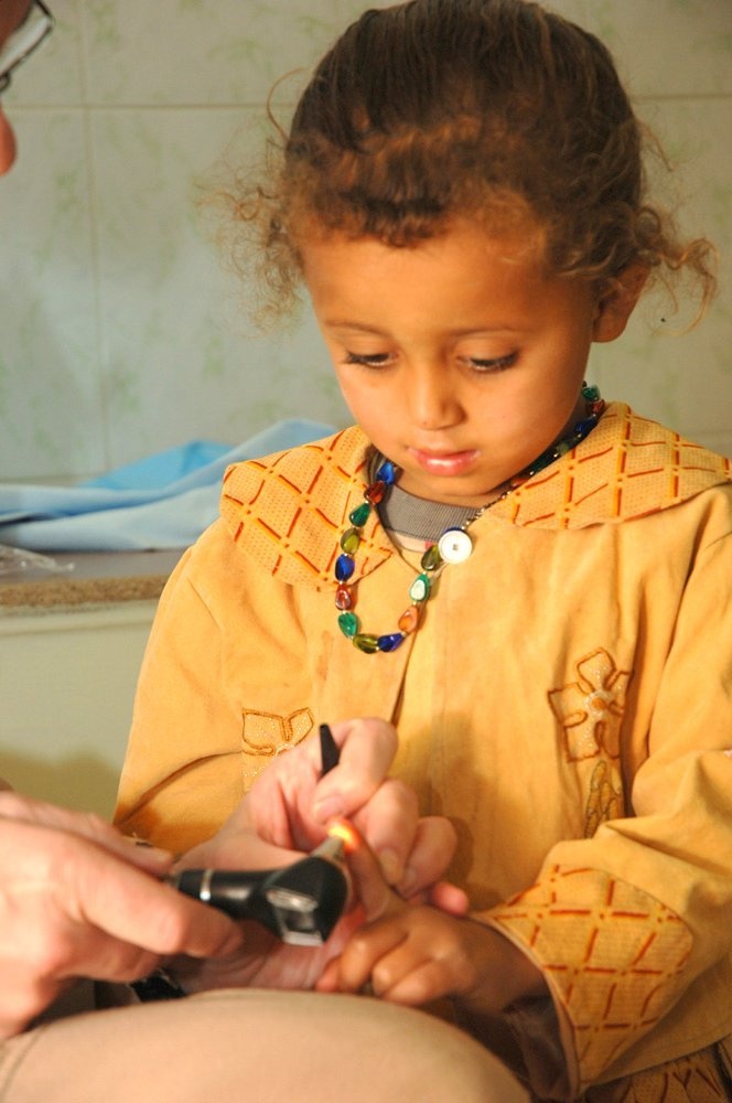 Dr. Guliuzza uses an otoscope to put a young Iraqi patient at ease