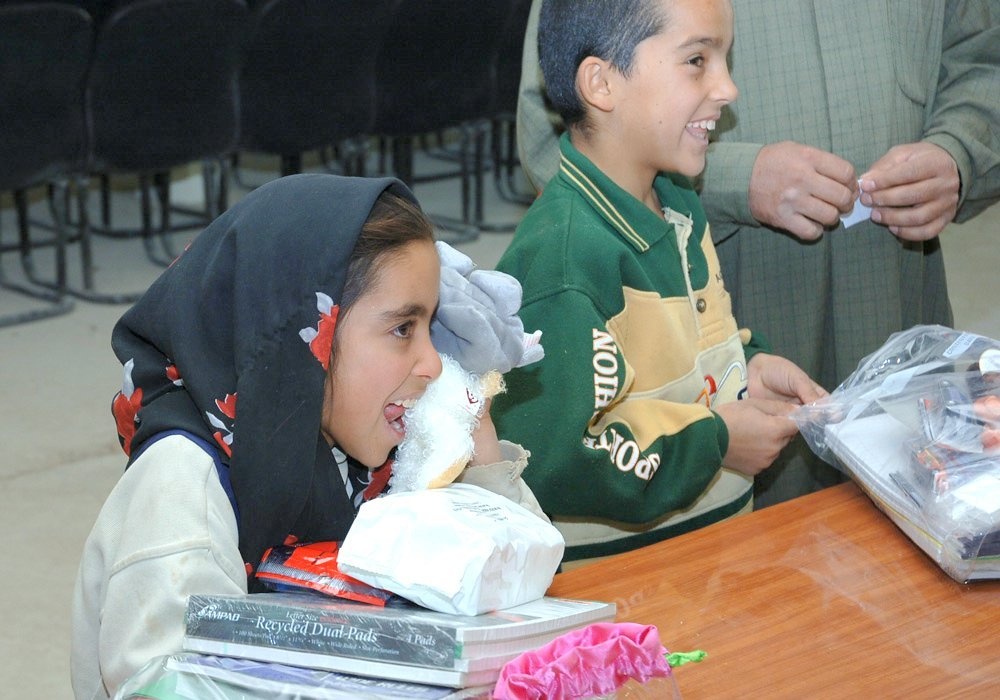 Two young Iraqi children receive free school supplies and toys
