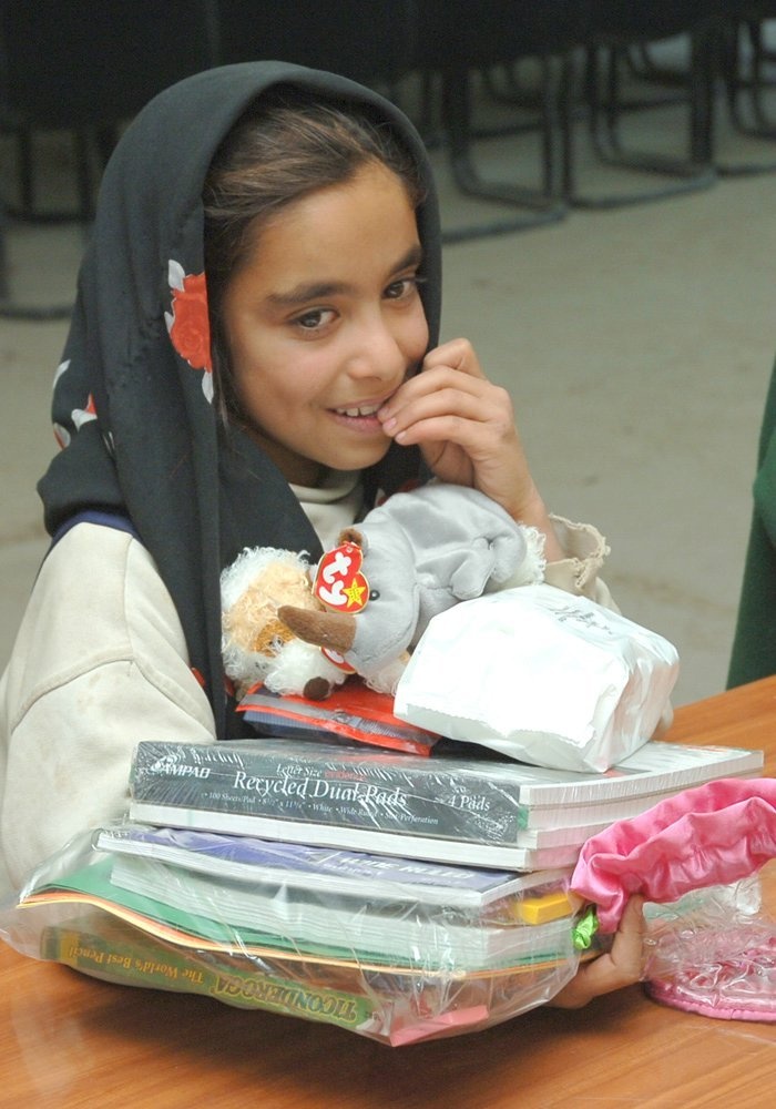 A young Iraqi girl receives free school supplies and toys