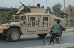 An Iraqi boy stops his bicycle to get a closer look at some Soldiers passin
