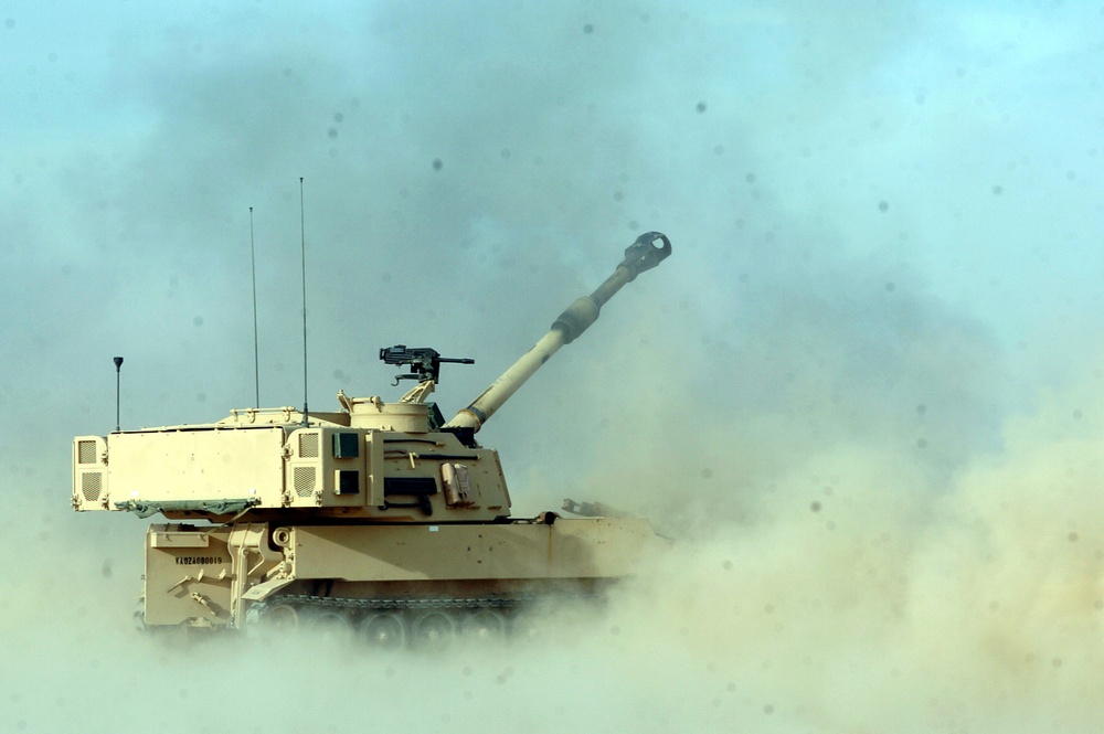 A M-109A6 Paladin is engulfed in dust, sand and smoke