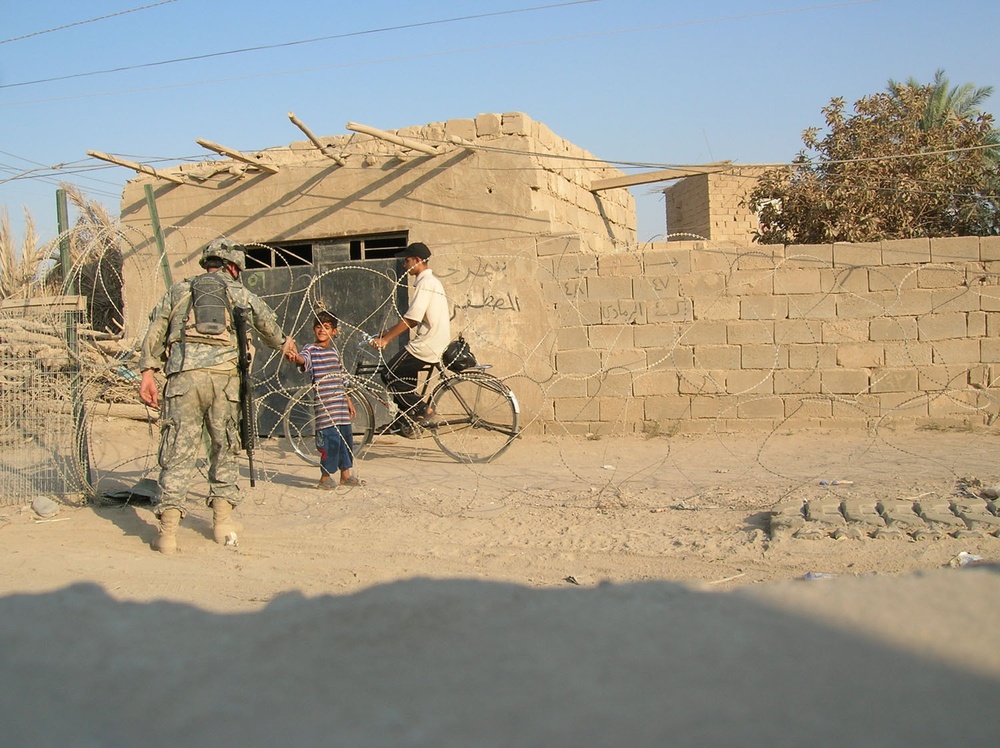 A Soldier greets two boys near a checkpoint in Ramadi