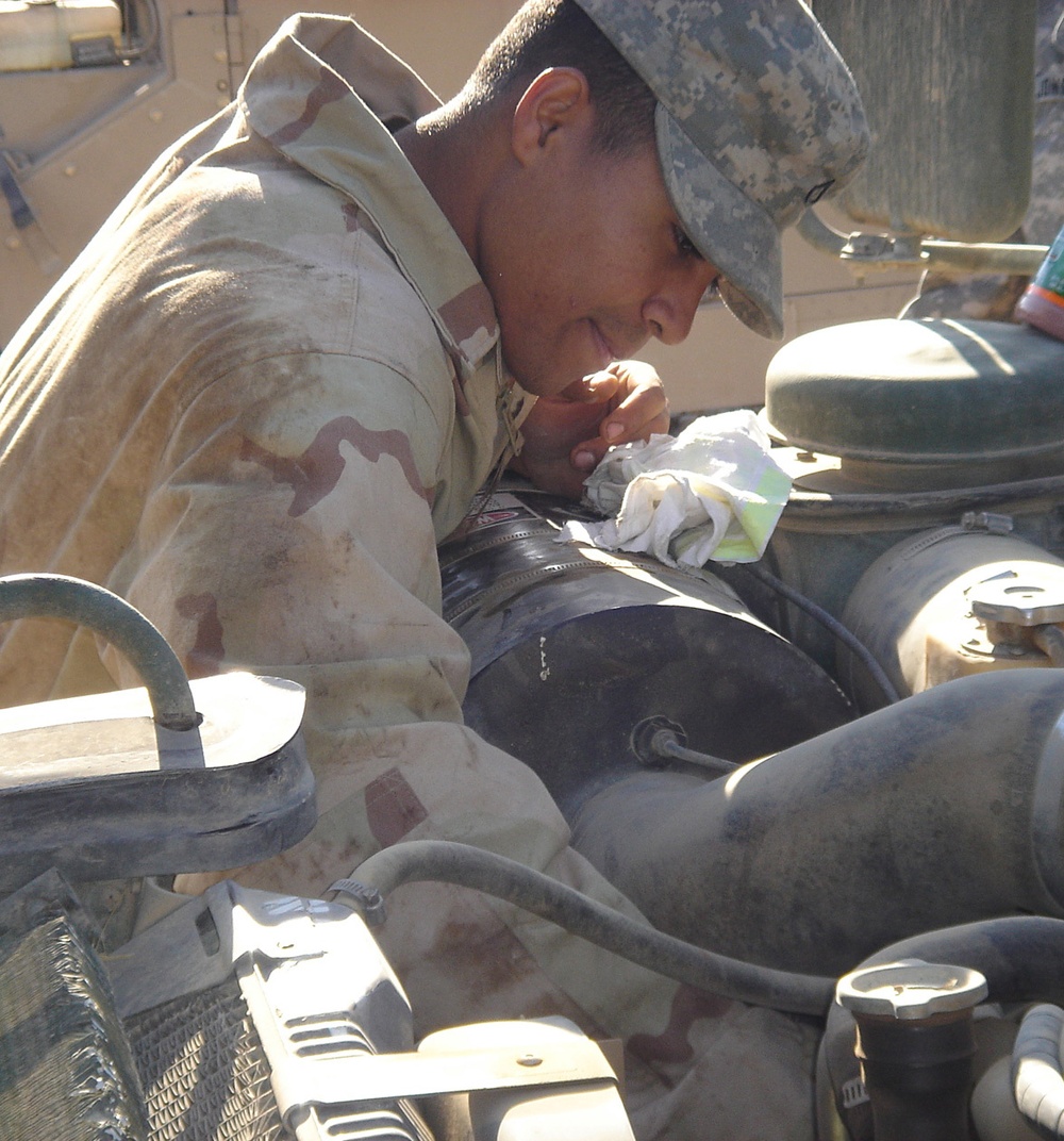 Pfc. Cedano checks the oil on a Humvee