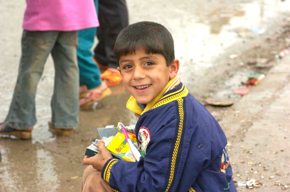 An Iraqi boy sits with a stockpile of toys and candy