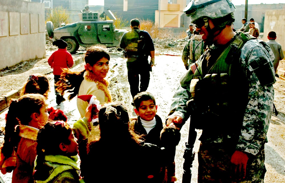 Sgt. Warren shakes hands and jokes with some Iraqi children