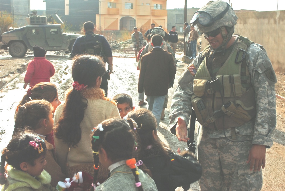 Sgt. Warren shakes hands and jokes with some Iraqi children