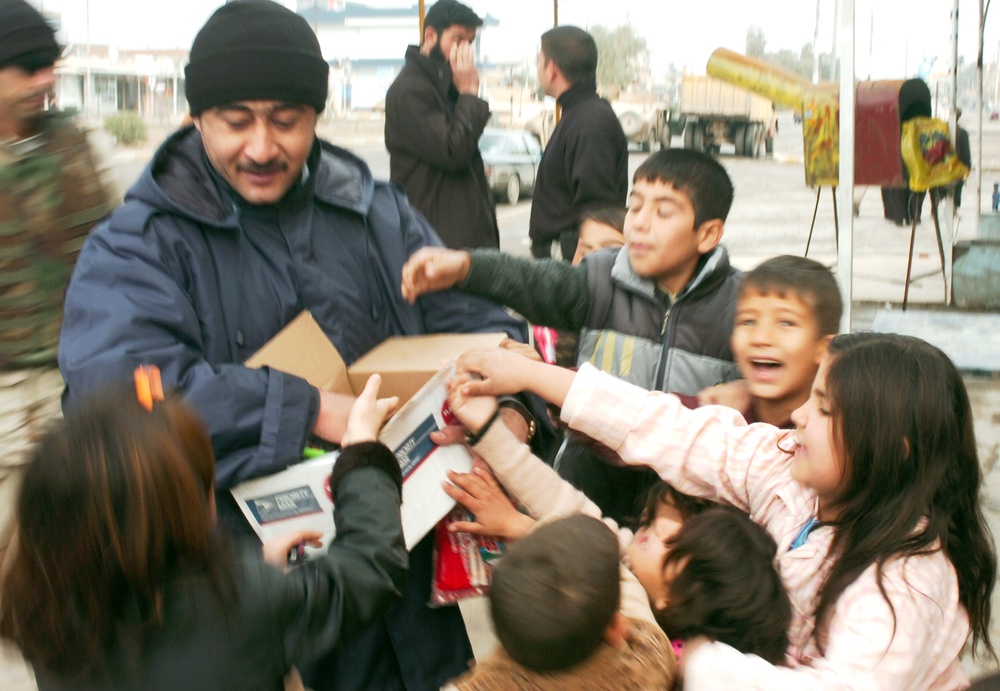 An Iraqi police officer hands out candy and toys to children