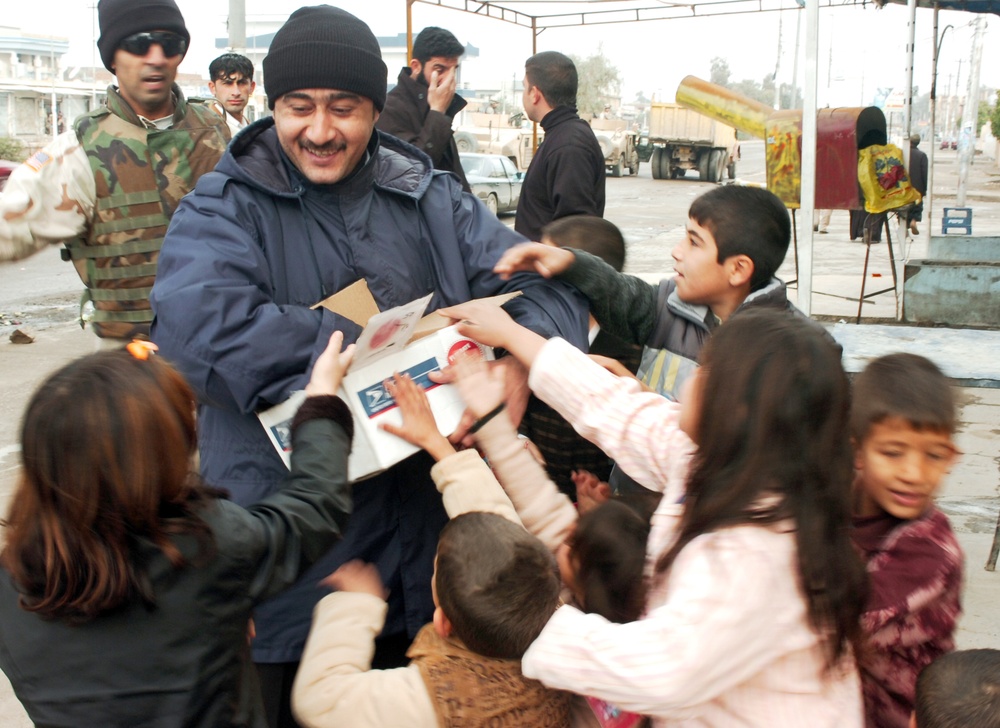 An Iraqi police officer hands out candy and toys to children