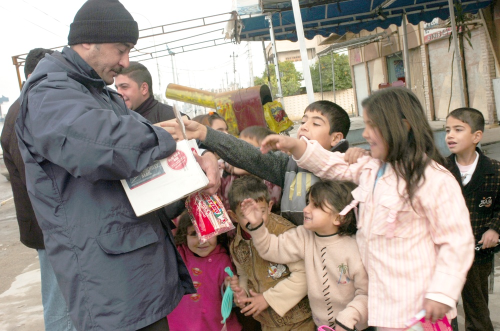 An Iraqi police officer hands out candy and toys to children