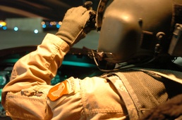 A CH-47 Chinook pilot adjusts his night vision goggles