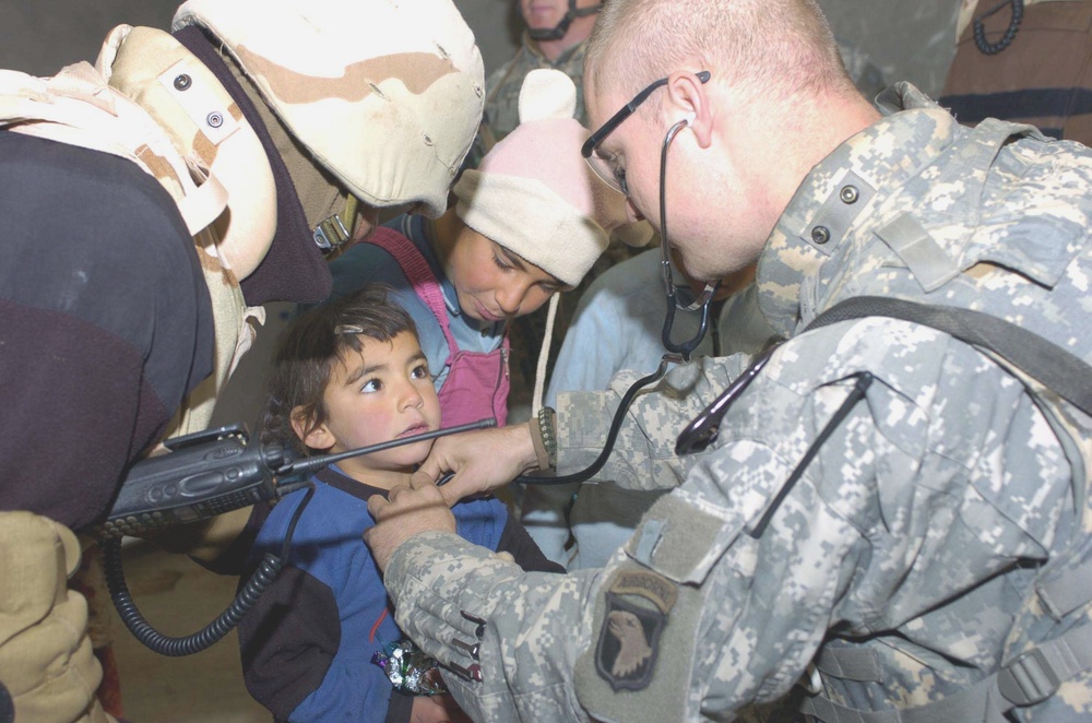 Spc. Radcliff listens for signs of asthma in a young Iraqi girl