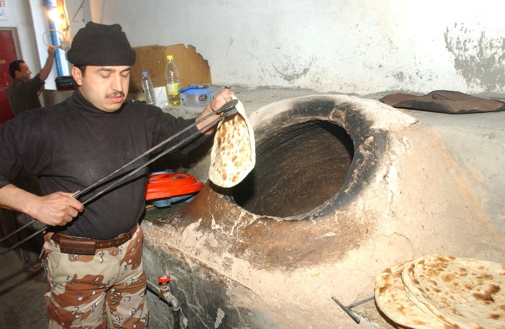 An Iraqi Army cook prepares bread for dinner