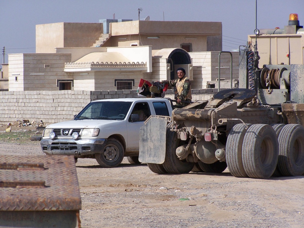 An Iraqi Soldier provides security for others as they procure concrete barr