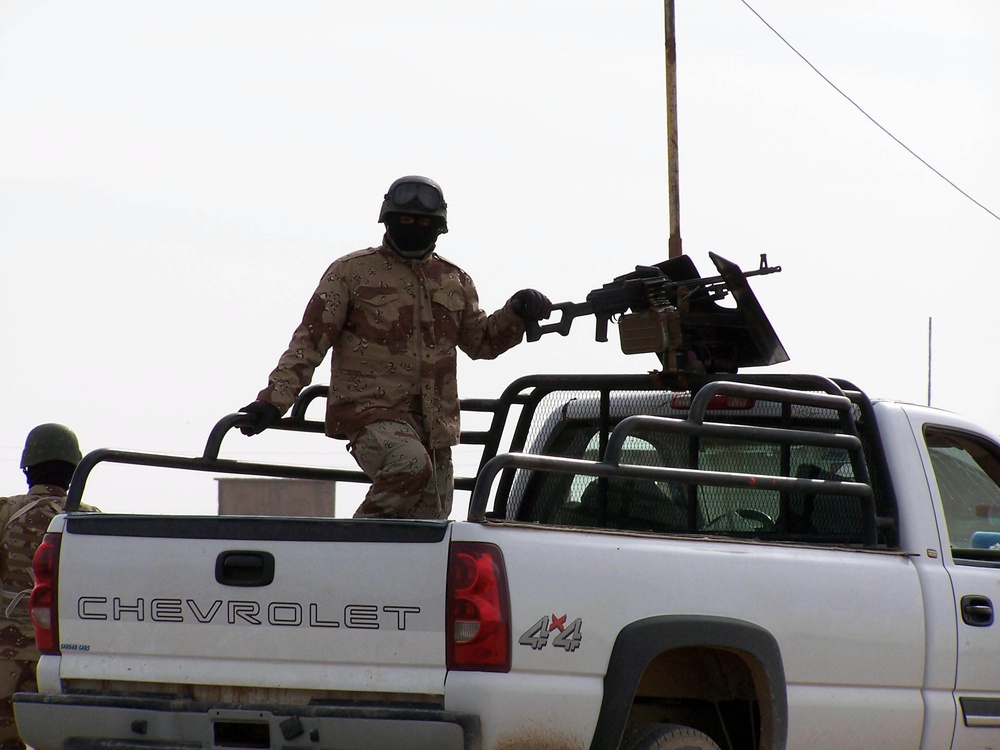 An Iraqi Soldier provides security for others as they procure concrete barr