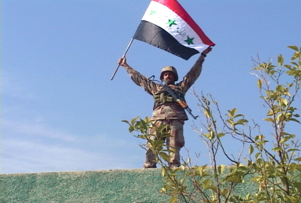 An Iraqi Soldier displays his country's flag