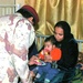 An Iraqi Army officer hands the mother of a sick Iraqi girl a bag of snacks