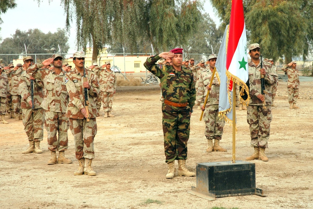 The graduation class cycle 22 salutes during the Iraqi national anthem