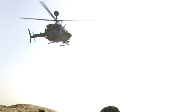 An OH-58, Kiowa Helicopter provides security for ground forces
