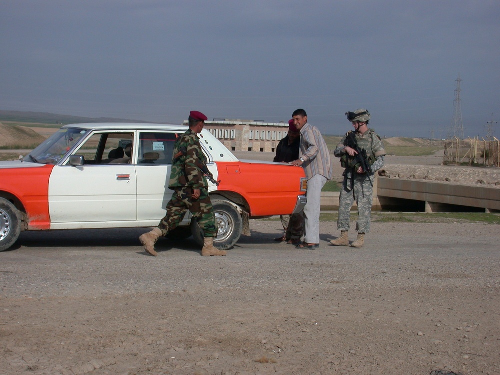 Pfc. Clinton Roberts and Iraqi soldiers inspect a vehicle