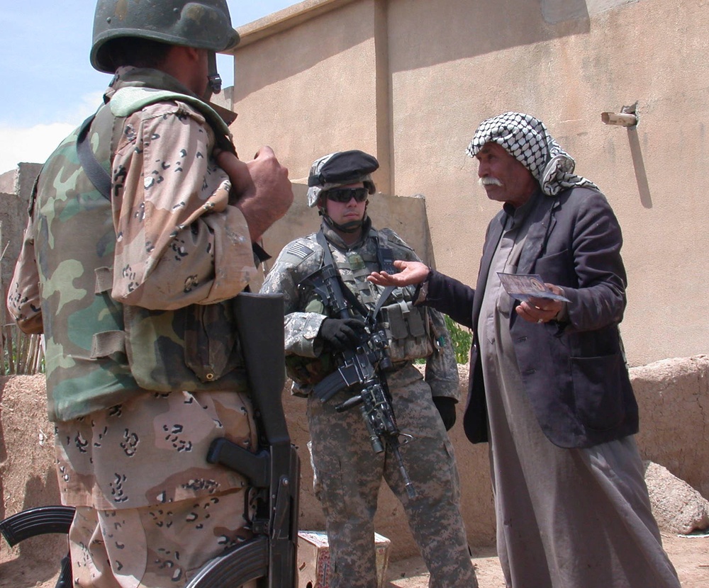 Iraqi Army soldiers and coalition forces speak to a farmer in Ma