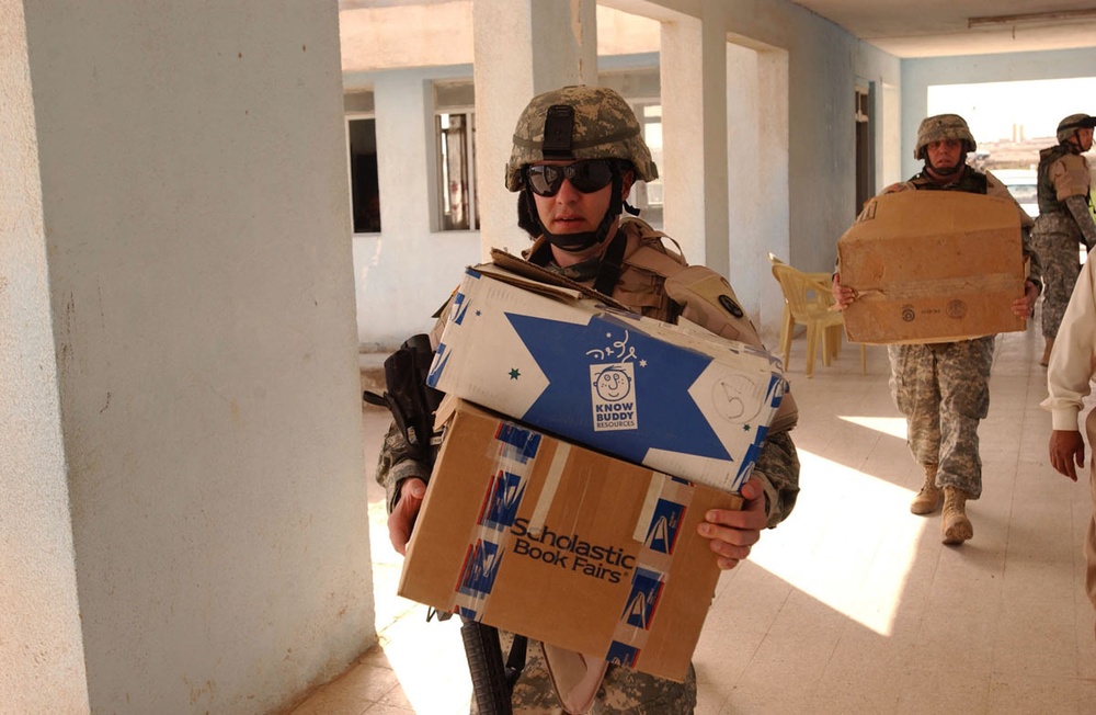 Staff Sgt. Dougherty Carries Boxes of School Supplies