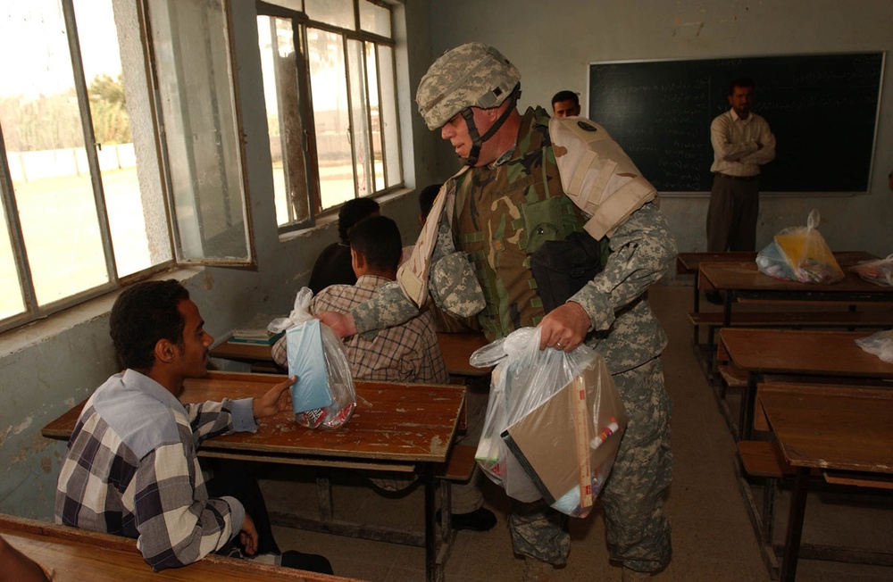 Chaplain (Maj.) McClearn hands bags of school supplies to students