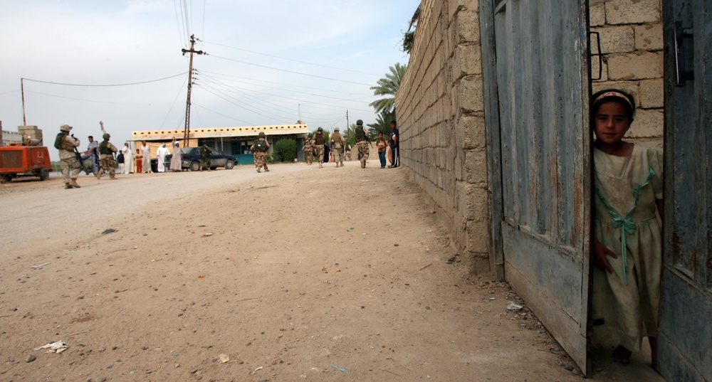 Small Iraqi girl looks out from her gate