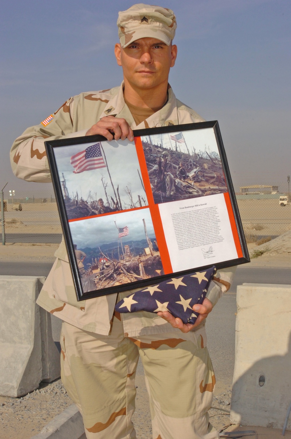 CAMP ARIFJAN, Kuwait - Sgt. Scott Leber, an operations NCO with the 385th Signal Company, holds the flag from &quot;Hamburger Hill&quot; and a plaque containing pictures of his uncle, former Spc. Joe Leber, with the raised flag on the hill in May 1969. Scott flew t