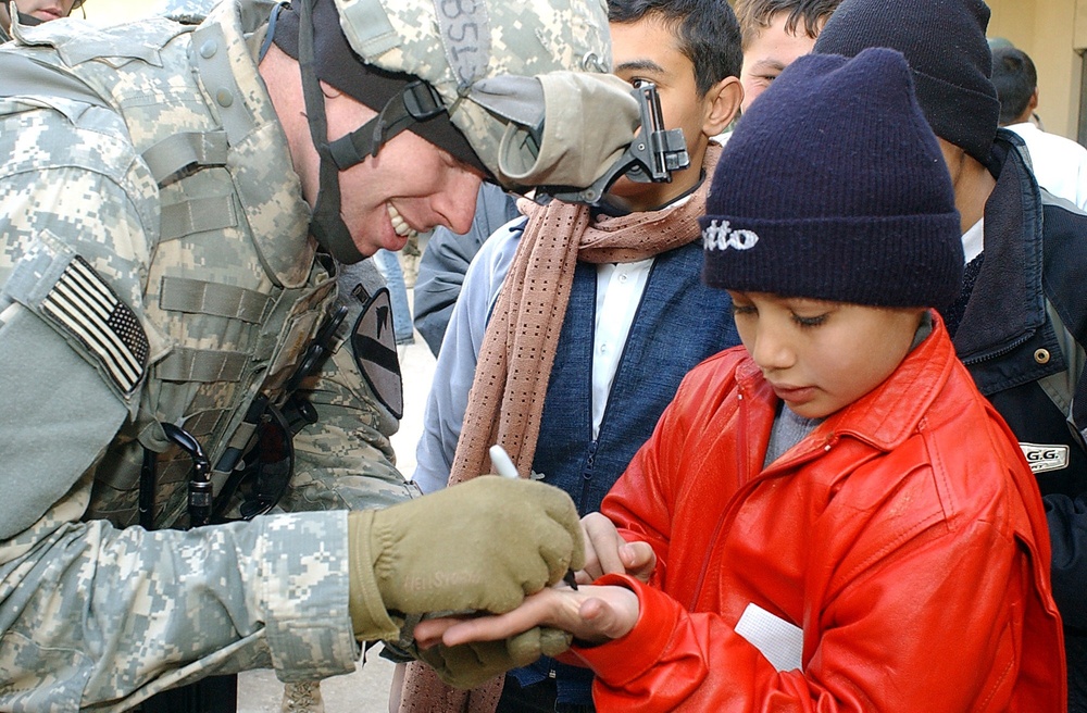 Soldiers hand out school supplies at a boys' school in Mosul