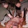 Military personnel in MARPAT camouflage uniforms are conducting a combat casualty care (TCCC) training exercise using a realistic medical simulation mannequin. The mannequin is equipped with simulated wounds, blood, and a tourniquet to replicate battlefield trauma scenarios. This appears to be a formal training drill in an indoor facility.