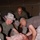 Military personnel in desert camouflage uniforms are conducting what appears to be a combat casualty care or trauma training exercise. They are gathered around a medical training mannequin/simulator that has simulated wounds and a needle decompression device inserted into the chest. The setting appears to be inside a military tent or temporary structure.