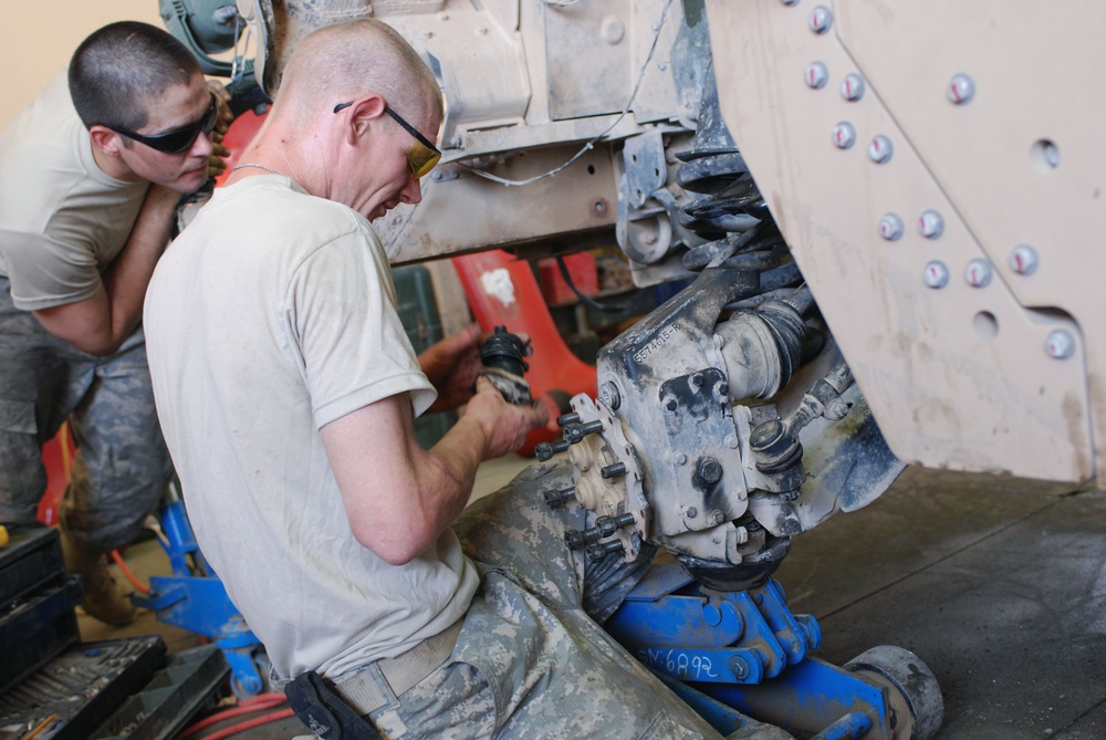 Mechanics work on up-armored Humvee