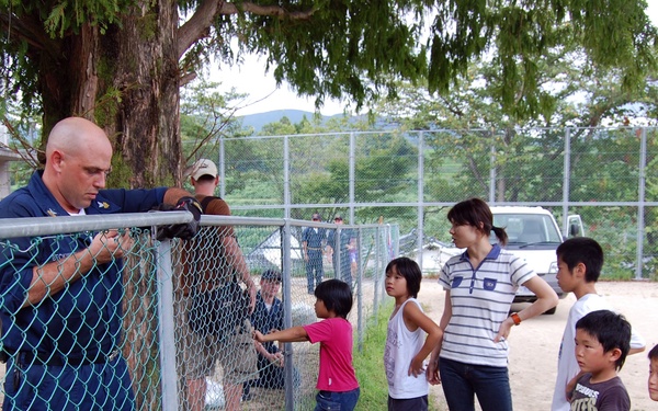 Japanese Children watch as sailors repair Tenshin-ryo Children's hom