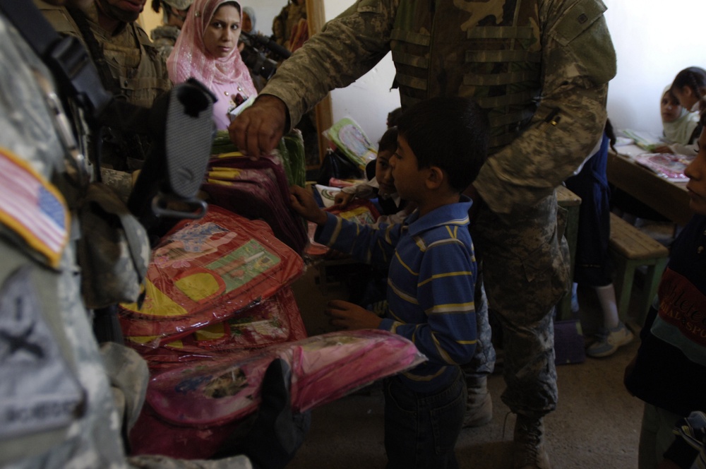 Soldiers hand out school supplies to local Iraqi children