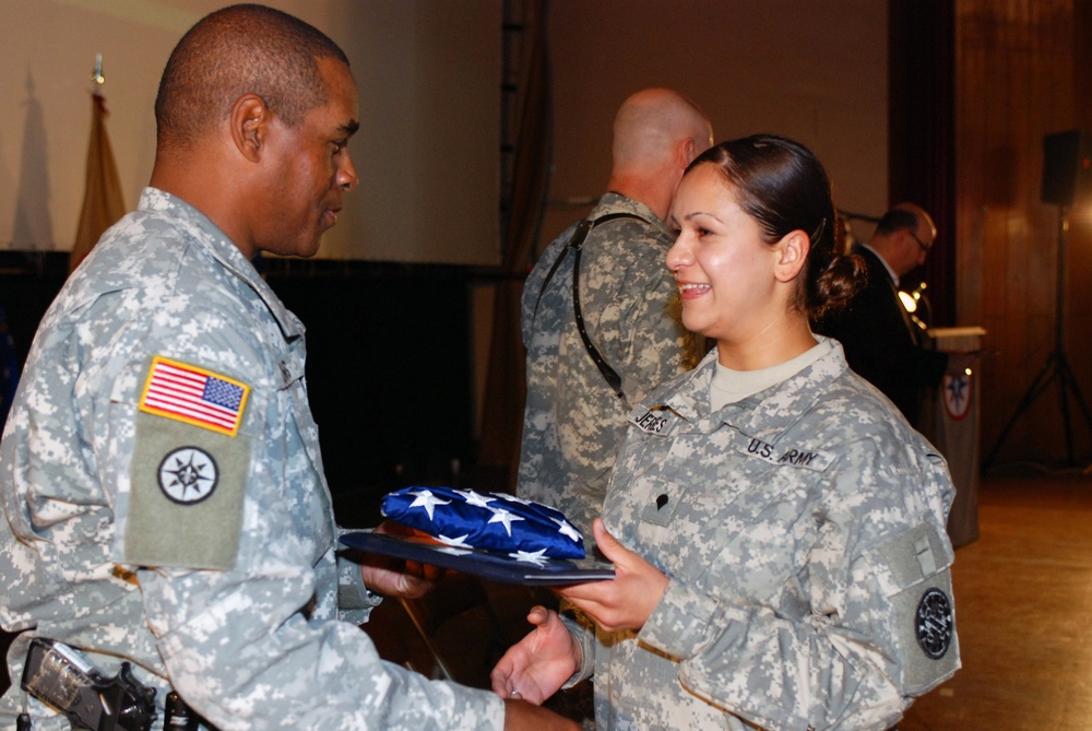 Spc. Lina Jergees, a linguist with the 177th Military Police Brigade, receives a U.S. flag from the 316th Expeditionary Sustainment Command senior enlisted leader, Command Sgt. Maj. Stacey E. Davis, Nov. 11, at Logistic Support Area. Along with 177 other