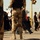 Iraqi Security Force take lead during Ashura movement in Kadhimiyah The image shows armed security personnel in desert camouflage uniforms standing at what appears to be a public gathering or crowd event. Civilians of various ages are walking past in the background. The scene suggests a security checkpoint or crowd control operation in an urban setting.